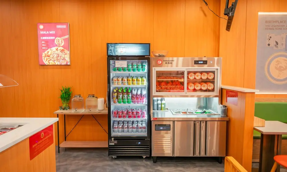 Area with beverage fridge, condiment station, and "MALA MIX" poster at YGF Malatang-Katy, a Chinese Restaurant in Katy