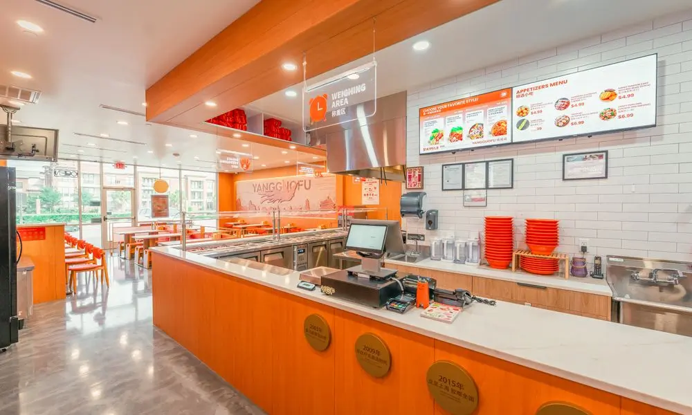 Checkout and food prep area with menu screens, orange plates, and modern design at YGF Malatang-Katy, a Chinese Restaurant in Katy