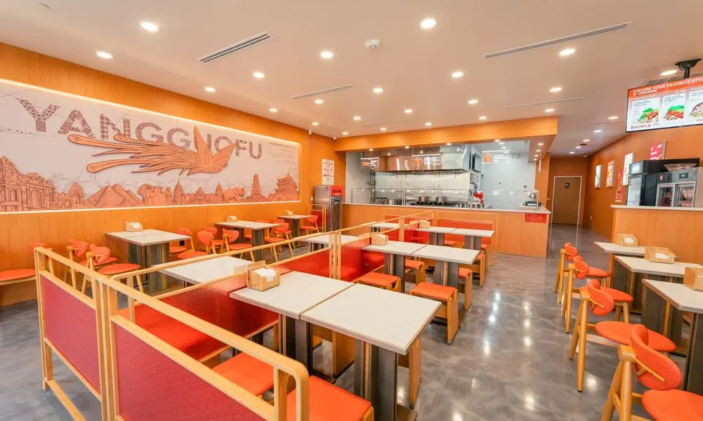 Restaurant interior with "YANGGUOFU" wall art, orange seating, and a modern layout at YGF Malatang-Katy, a Chinese Restaurant in Katy