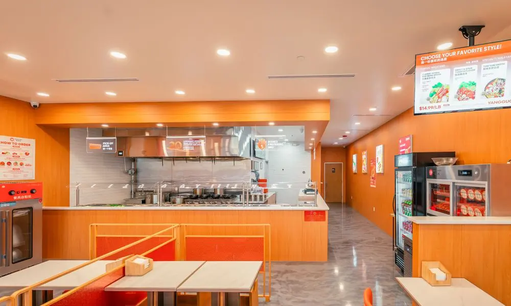 Kitchen and dining area with menu boards, refrigerators, and orange decor at YGF Malatang-Katy, a Chinese Restaurant in Katy