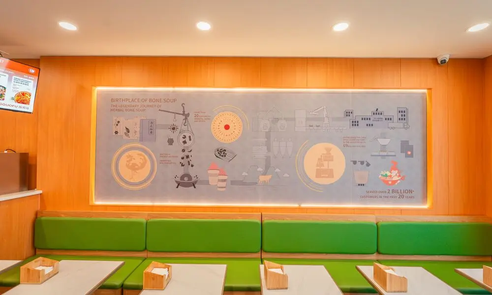 Interior of a bright restaurant with wooden walls, green booths, and dining tables at YGF Malatang-Katy, a Chinese Restaurant in Katy